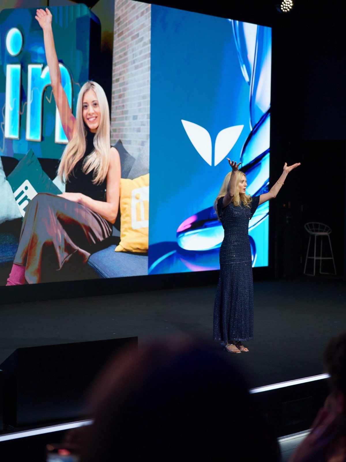 Sabrina Stocker on stage with her arms raised mid-talk